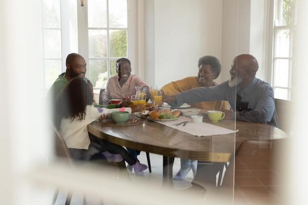 Immagine di una felice famiglia afroamericana di più generazioni che fa colazione. Famiglia e trascorrere del tempo di qualità insieme concetto.