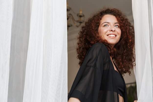 Immagine di una giovane donna allegra felice in costume da bagno lingerie in posa al chiuso in hotel di casa vicino alla tenda.