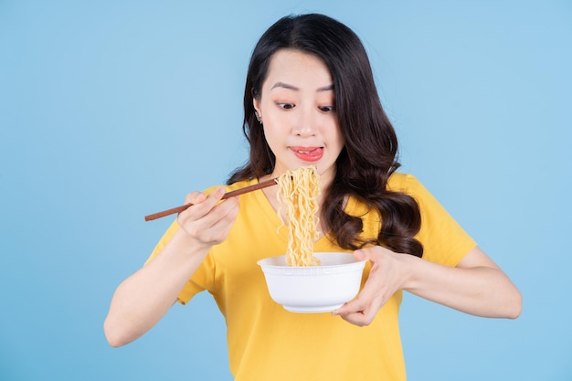 Immagine di una giovane donna asiatica che mangia spaghetti istantanei