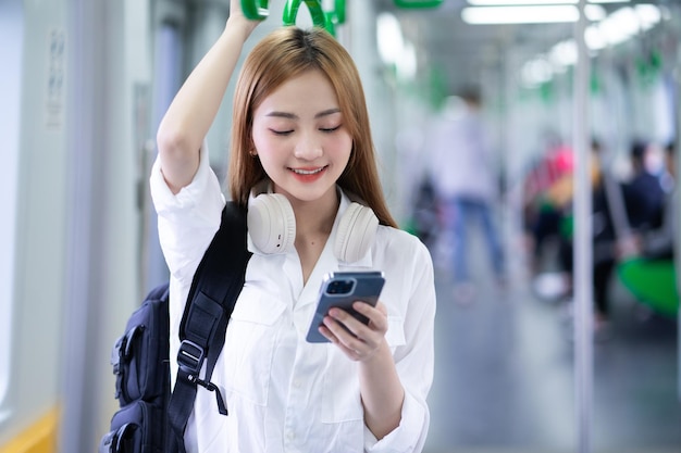 Immagine di una giovane donna asiatica che usa lo smartphone in metropolitana