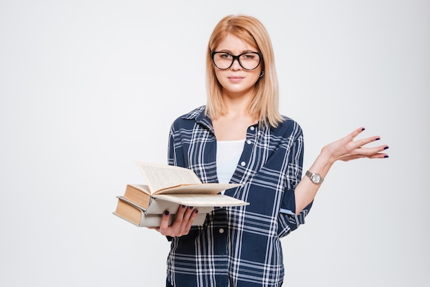 Immagine di una giovane donna confusa che legge libri isolati su uno sfondo bianco.