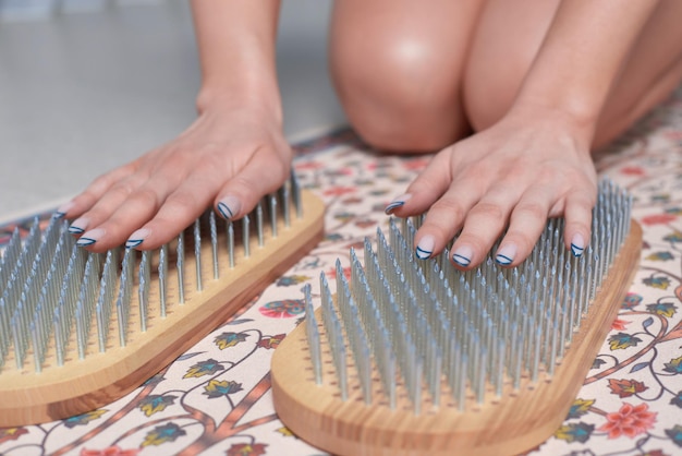 Immagine di una giovane donna in tuta da ginnastica seduta su una stuoia in uno studio luminoso che si prepara per la meditazione con una tavola da sadhu Il concetto di fitness yoga pilates