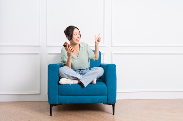 immagine di una giovane ragazza asiatica seduta sul divano di casa