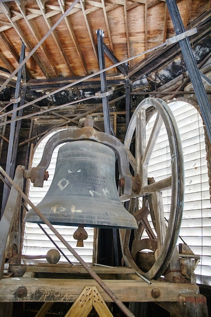 Immagine di una grande campana di metallo in una torre con meccanica e ingranaggi