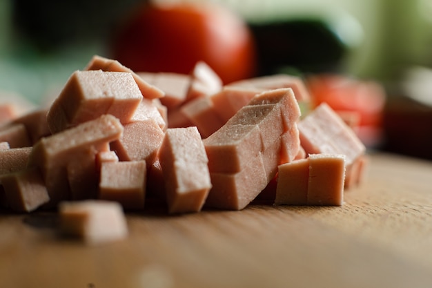 Immagine di una piccola pila di salsiccia affettata a cubo per cucinare su un tavolo di legno in cucina