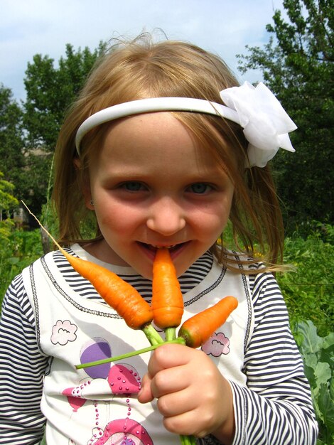 Immagine di una ragazza che morde la carota arancione matura