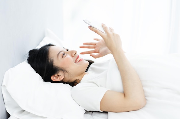 Immagine di una ragazza che usa il telefono a letto, al mattino