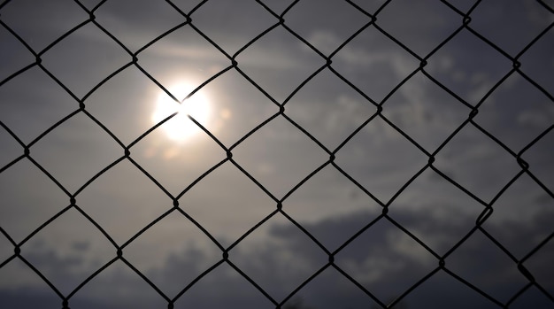 immagine di una recinzione metallica con maglia al tramonto