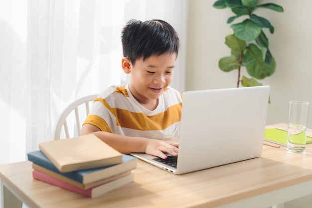 Immagine di uno studente preadolescente che studia con un laptop isolato a casa