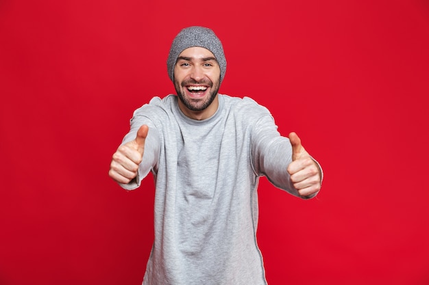 Immagine di uomo positivo 30 anni con stoppie che ride e mostra i pollici in su