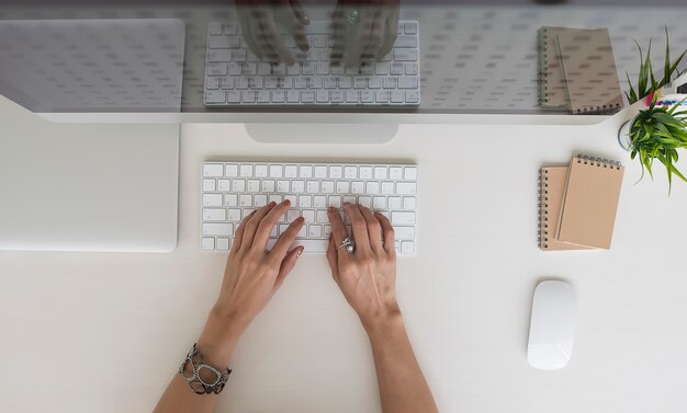 Immagine di vista superiore delle mani femminili che digitano sulla tastiera bianca