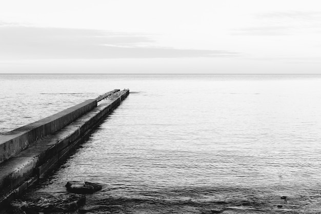 Immagine in bianco e nero di un molo di cemento sulla costa