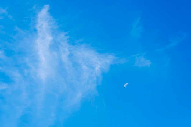 Immagine in formato verticale di una mezza luna distante isolata su un cielo blu
