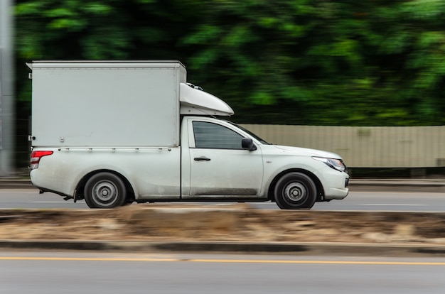 Immagine in movimento, piccolo camion bianco in esecuzione su strada per attività di logistica.