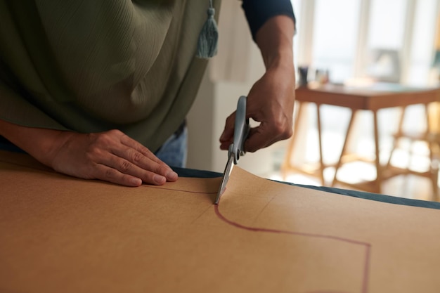 Immagine in primo piano di un sarto che taglia un modello di cucito su carta