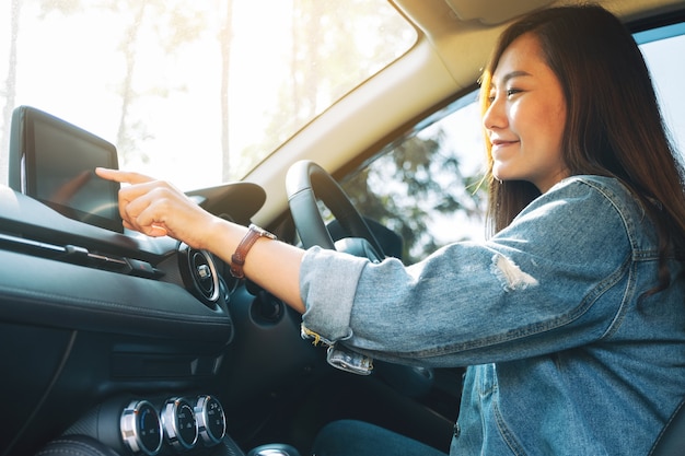 Immagine in primo piano di una bella donna che usa e punta il dito sullo schermo di navigazione mentre guida l'auto