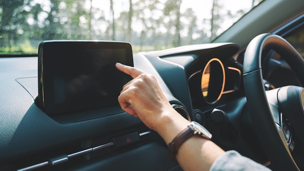 Immagine in primo piano di una donna che usa e punta il dito sullo schermo di navigazione mentre guida l'auto