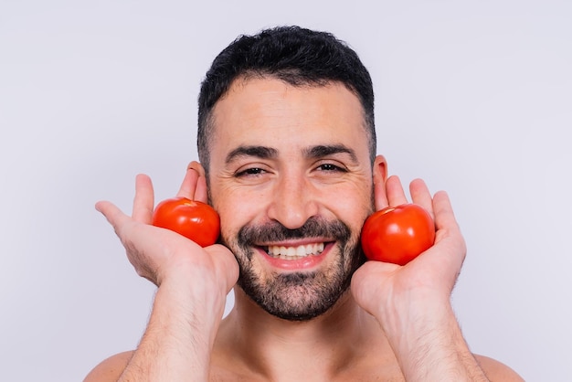 Immagine in studio completamente isolata da un giovane uomo nudo con biancheria intima e pomodoro