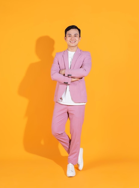 Immagine integrale del giovane uomo asiatico in piedi su sfondo arancione