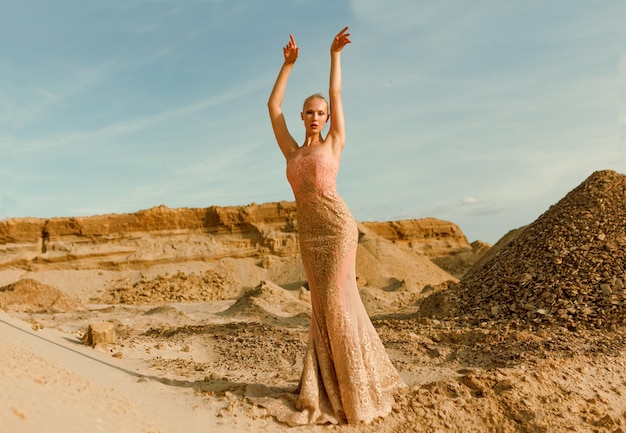 Immagine integrale di una splendida signora in bel vestito sottile in posa nel deserto al tramonto.