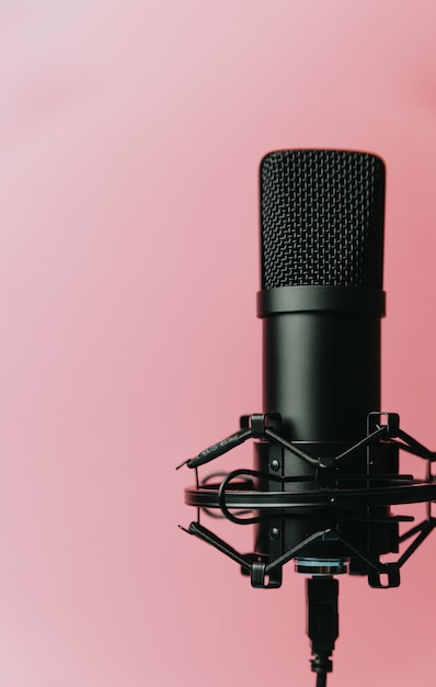 Immagine minimalista di un microfono in streaming su una parete rosa pastello con spazio di copia, concetto minimo