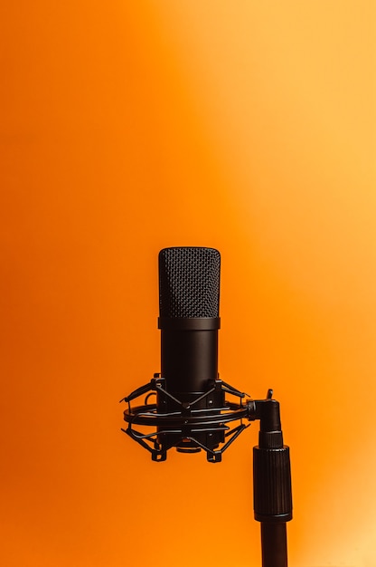 Immagine minimalista di un microfono in streaming su uno sfondo arancione con spazio di copia, concetto minimo