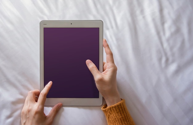 Immagine mockup di tavoletta digitale. La donna posa sul letto usando Tablet