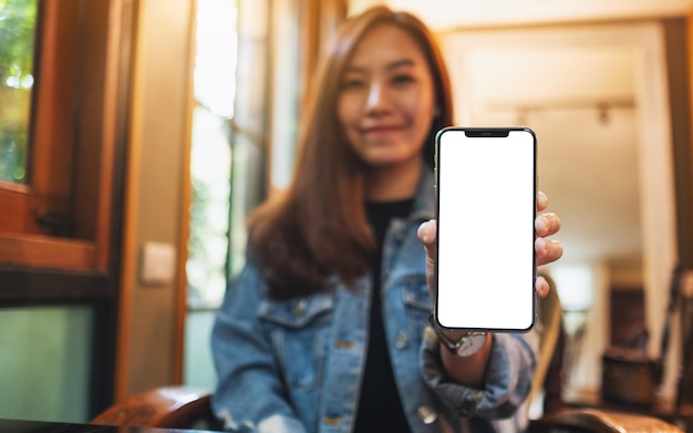 Immagine mockup di una bella donna asiatica che tiene e mostra un telefono cellulare con schermo bianco vuoto