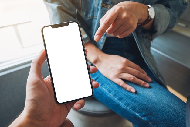 Immagine mockup di una donna che indica un telefono cellulare bianco con uno schermo desktop nero vuoto nella mano di qualcuno