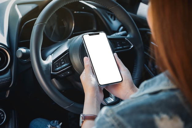 Immagine mockup di una donna che tiene e usa il telefono cellulare con lo schermo vuoto mentre guida l'auto