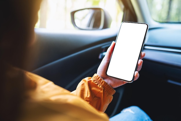 Immagine mockup di una donna che tiene e utilizza il telefono cellulare con schermo vuoto in macchina