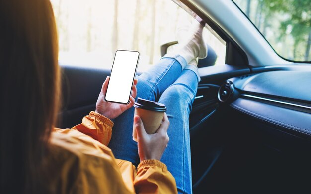 Immagine mockup di una donna che tiene e utilizza il telefono cellulare con schermo vuoto mentre beve caffè e si sdraia in macchina