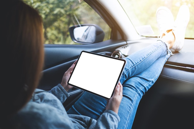 Immagine mockup di una donna che tiene e utilizza una tavoletta digitale con schermo vuoto in macchina