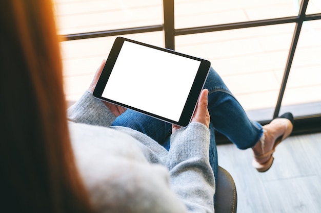 Immagine mockup di una donna che tiene in mano un tablet pc nero con schermo bianco vuoto