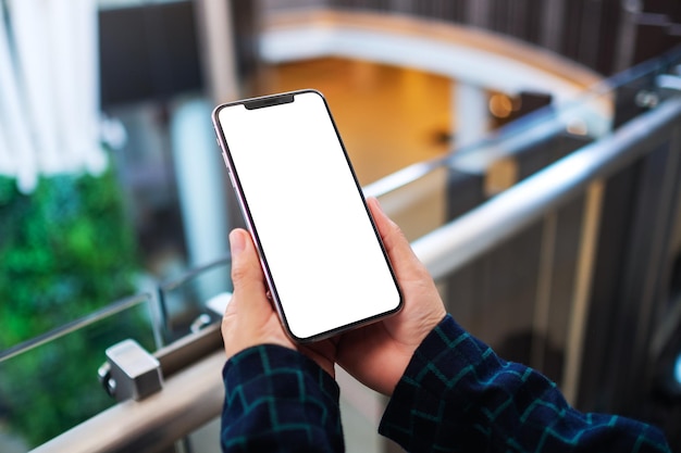 Immagine mockup di una donna che tiene in mano un telefono cellulare con uno schermo bianco vuoto all'interno