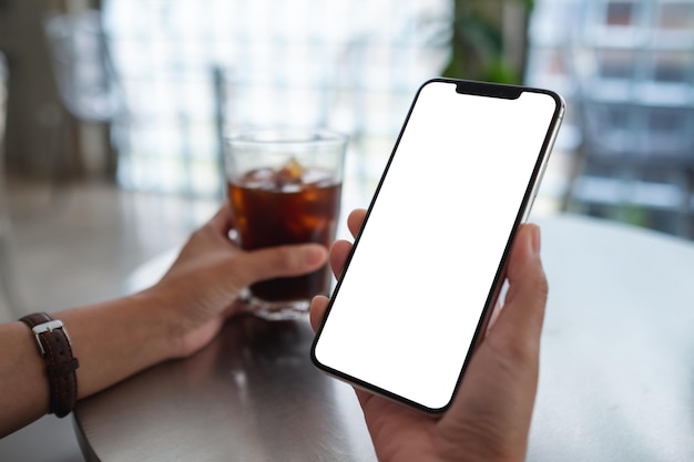 Immagine mockup di una donna che tiene in mano un telefono cellulare con uno schermo desktop bianco vuoto mentre beve caffè