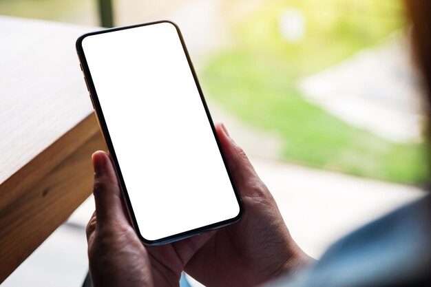 Immagine mockup di una donna che tiene in mano un telefono cellulare con uno schermo desktop bianco vuoto
