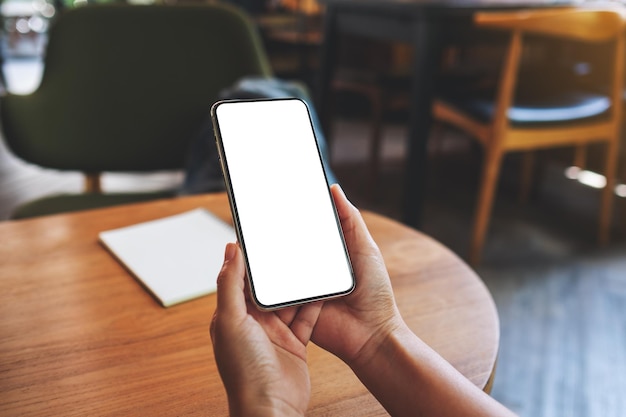 Immagine mockup di una donna che tiene in mano un telefono cellulare con uno schermo desktop bianco vuoto