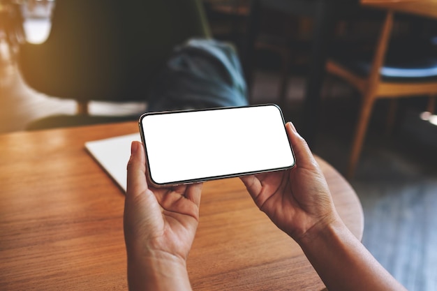 Immagine mockup di una donna che tiene in mano un telefono cellulare con uno schermo desktop bianco vuoto