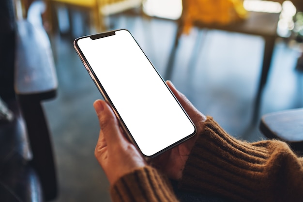 Immagine mockup di una donna che tiene in mano un telefono cellulare nero con schermo desktop vuoto