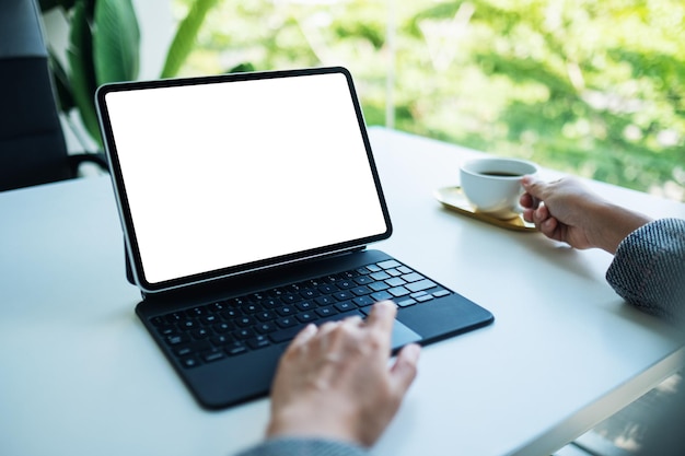 Immagine mockup di una donna che tocca il touchpad del tablet con lo schermo desktop bianco vuoto come un computer mentre beve caffè