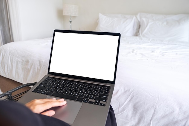 Immagine mockup di una donna che usa e digita sul computer portatile con la tastiera bianca vuota dello schermo del desktop in camera da letto