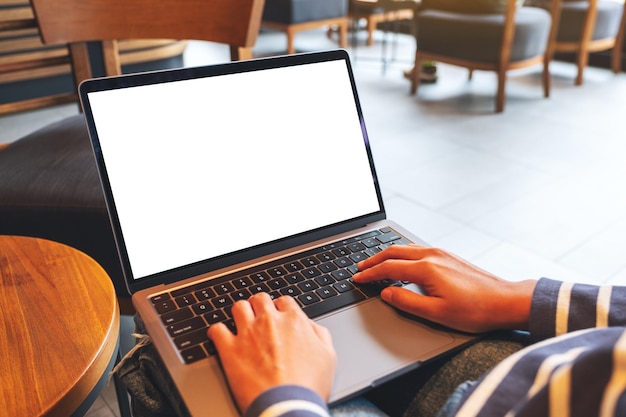 Immagine mockup di una donna che usa e digita sulla tastiera del computer portatile con lo schermo del desktop bianco vuoto nella caffetteria
