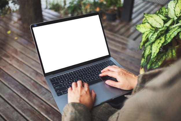 Immagine mockup di una donna che utilizza e digita su un computer portatile con schermo desktop bianco vuoto all'aperto