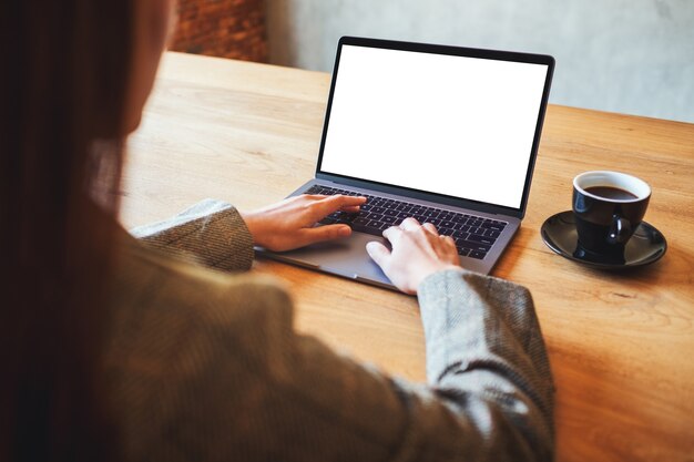 Immagine mockup di una donna che utilizza e digita sul computer portatile con schermo desktop bianco vuoto in un caffè