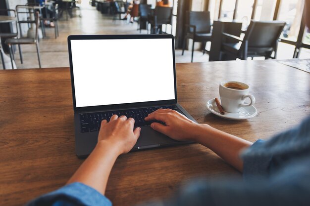 Immagine mockup di una donna che utilizza e digita sul computer portatile con schermo desktop bianco vuoto in un caffè