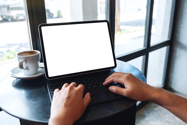 Immagine mockup di una donna che utilizza e digita sulla tastiera del tablet con uno schermo desktop bianco vuoto come un computer sul tavolo