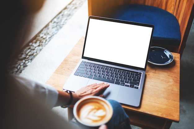 Immagine mockup di una donna d'affari che usa e tocca il touchpad del laptop con uno schermo desktop bianco vuoto al bar