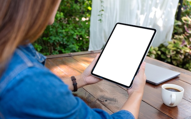 Immagine mockup di una donna in possesso di tablet digitale con schermo desktop bianco vuoto in mezzo alla natura