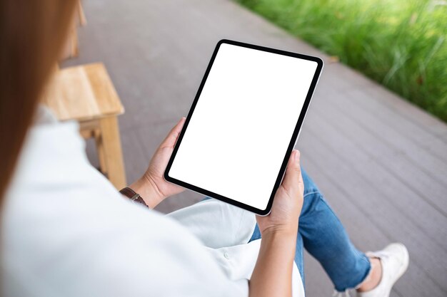 Immagine mockup di una donna in possesso di tablet digitale con schermo desktop bianco vuoto in mezzo alla natura